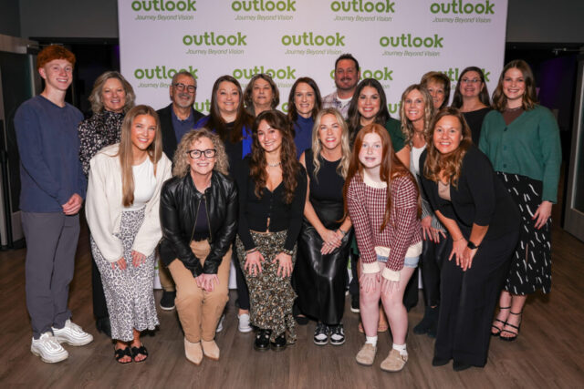 Volunteers smiling in front of an Outlook backdrop.