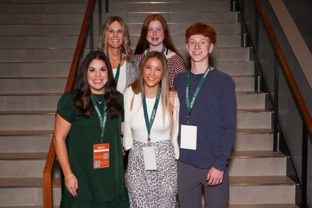 A group shot of five gala volunteers smiling in front of the venue's stairs.