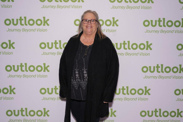 A woman smiling in front of an Outlook backdrop.