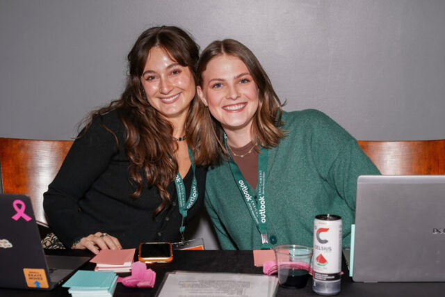 Two woman volunteers leaning in and smiling.