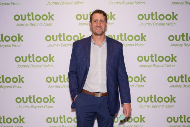 Adam smiling in front of an Outlook backdrop.
