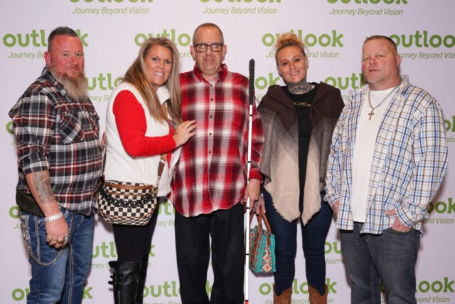 Keli and guests are smiling in front of an Outlook backdrop.