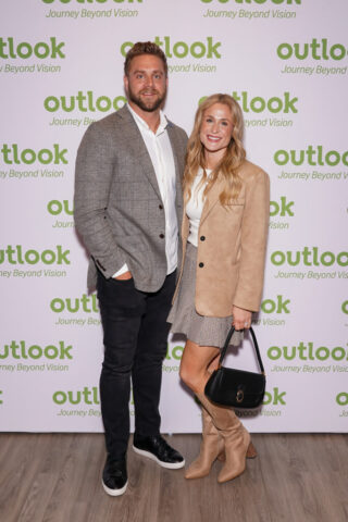 Sean and woman guest are smiling in front of an Outlook backdrop.