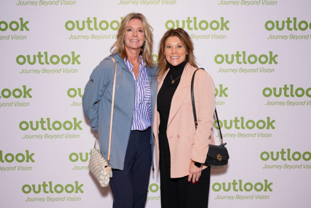 Two women smiling in front of an Outlook backdrop.