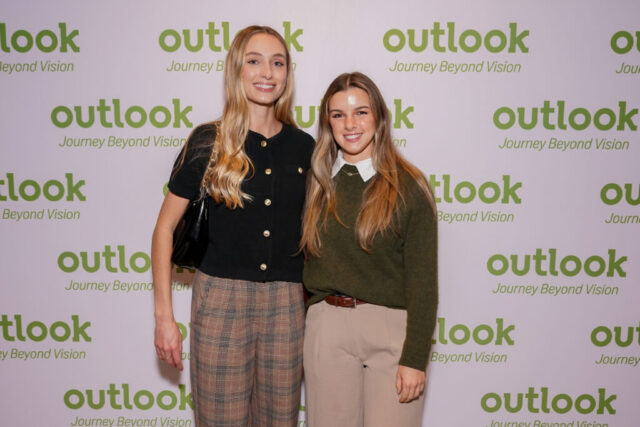 Bailey and her female guest are smiling in front of an Outlook backdrop.
