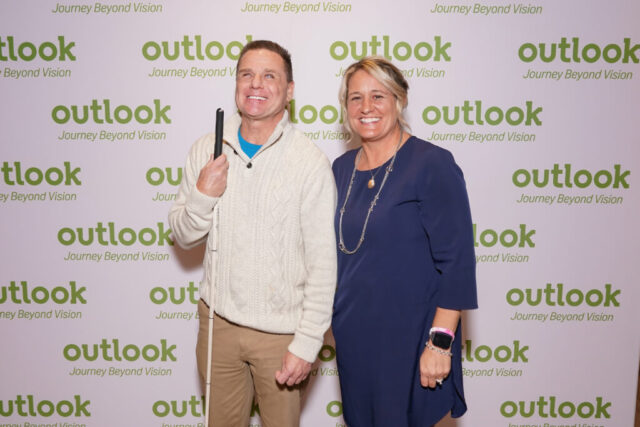 Kenny and Nina are smiling in front of an Outlook backdrop.