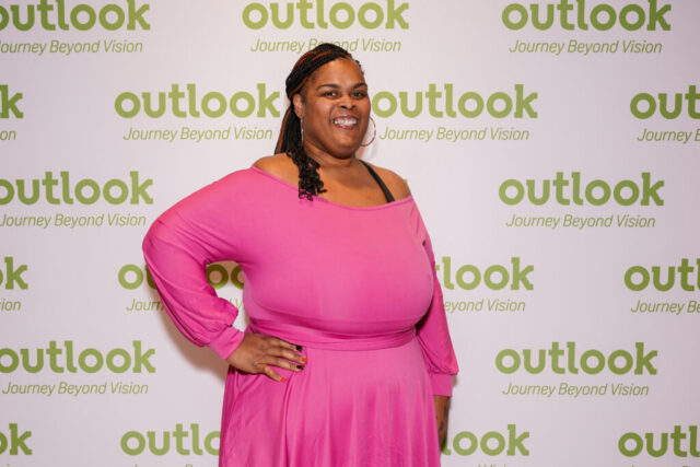 A woman smiling in front of an Outlook backdrop.