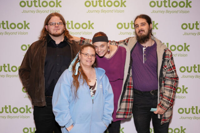 Michelle and her guests are smiling in front of an Outlook backdrop.