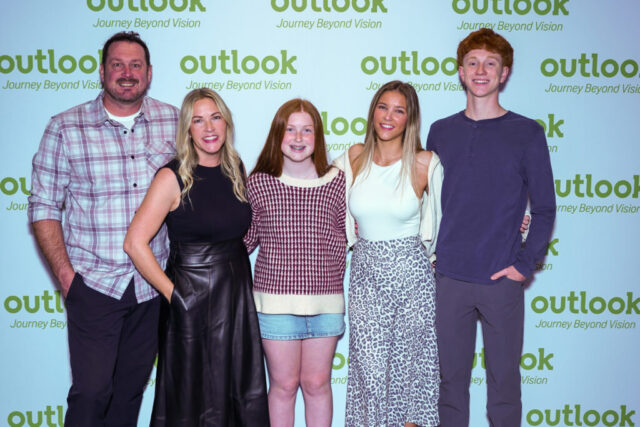 Cassie and her group are smiling in front of an Outlook backdrop.
