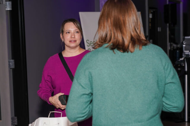A woman talking to another woman next to the silent auction.