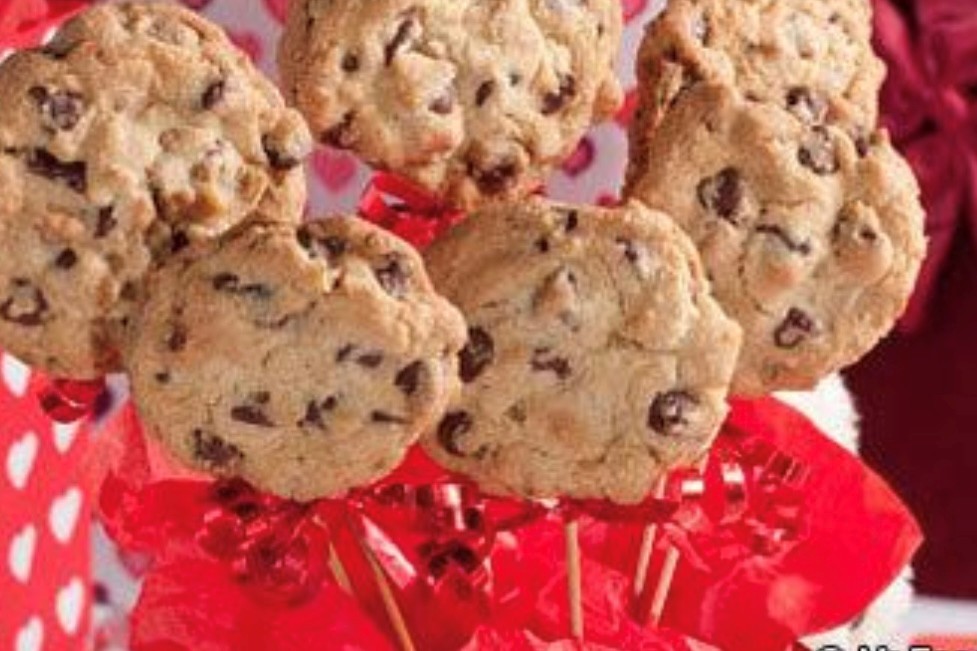 A zoomed in picture of chocolate chip cookies engulfed in light red tissue paper.