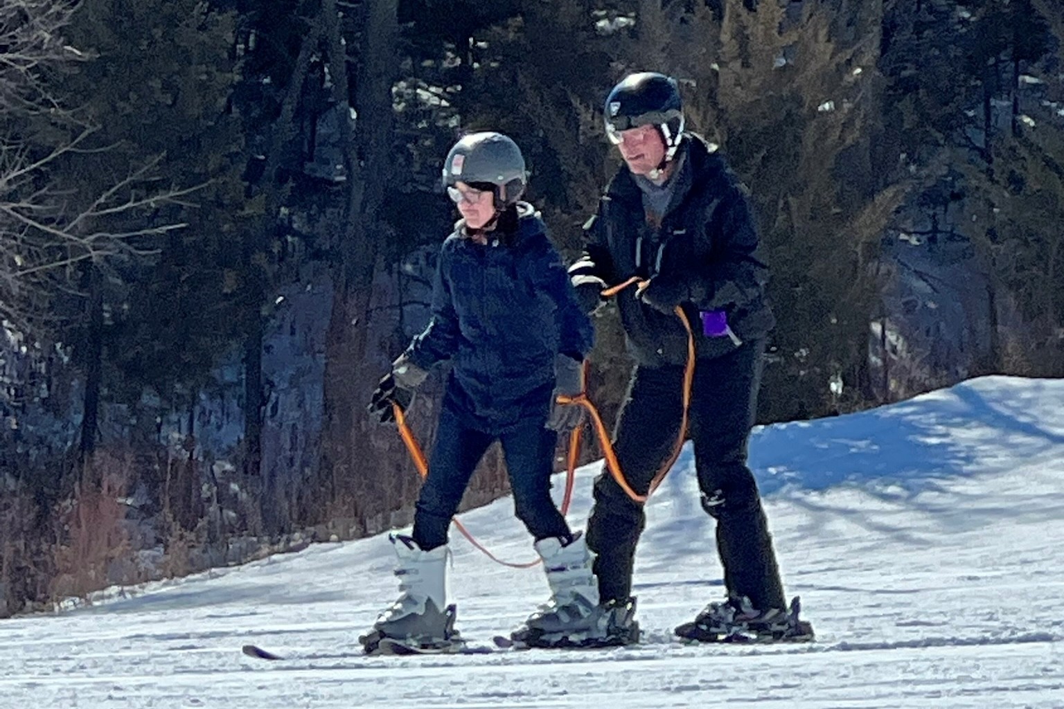 Camille skiing down a snowy hill, her guide is skiing slightly behind her.