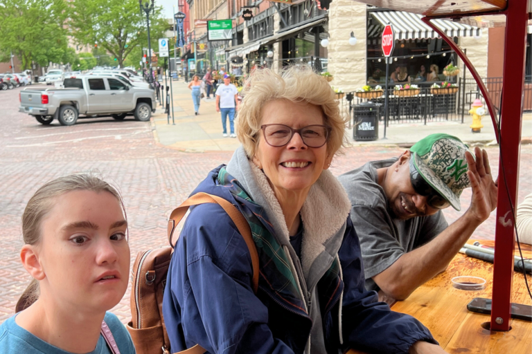 Julie is in the middle of two individuals smiling on a party patio ride.
