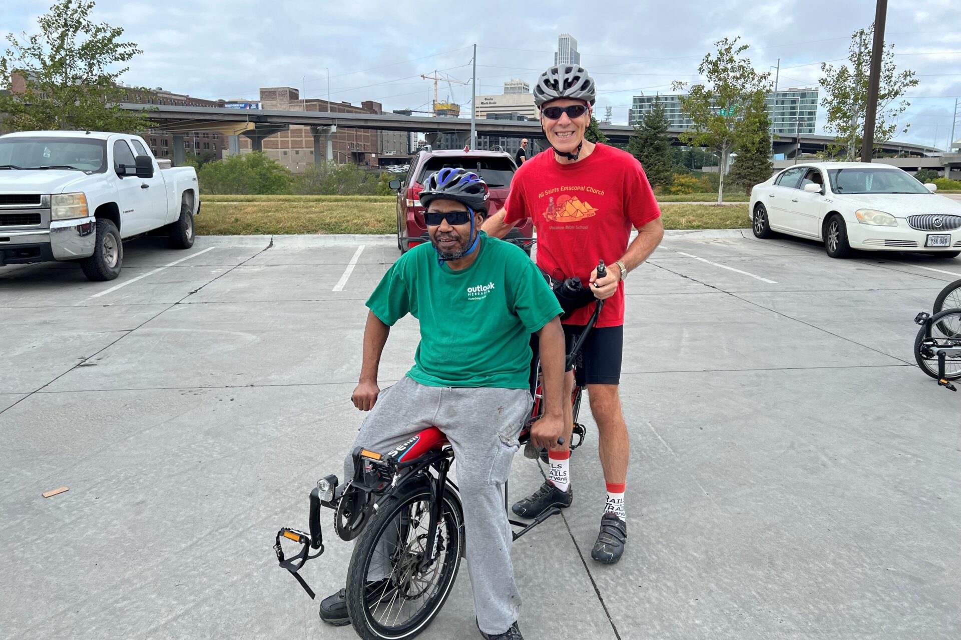 Alex and Rob on a primo tandem bike. Alex pedals in a seated position in front and Rob pedals from an upright position in the back.
