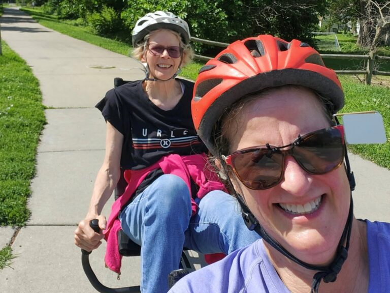A selfie style picture of Julie and a volunteer bike captain on a recumbent bike.