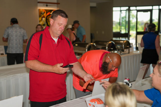 Two men at the raffle ticket table purchasing tickets.