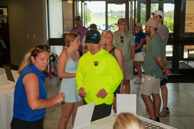 Steve has the Blind Golfers Clinic team behind him as he talks to Nina at check in.