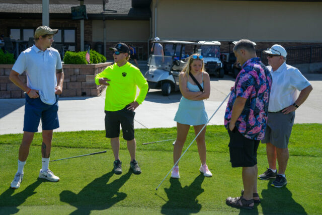 Brad, Steve, Anna, Ross, and a male guide standing on the green.