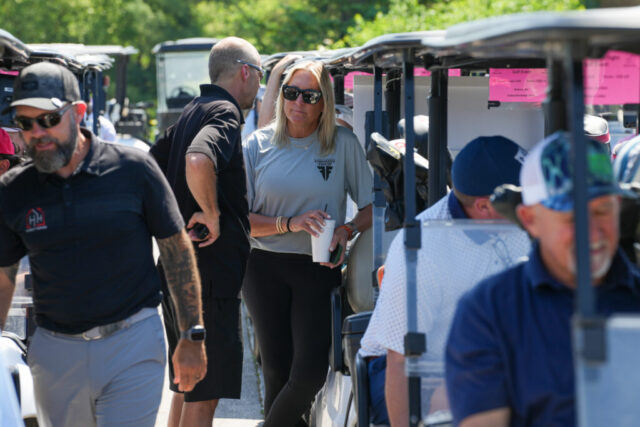 A lady from Forsmans Finest and a man are chatting by golf carts.