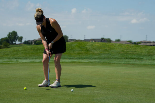 A lady is putting on the green.