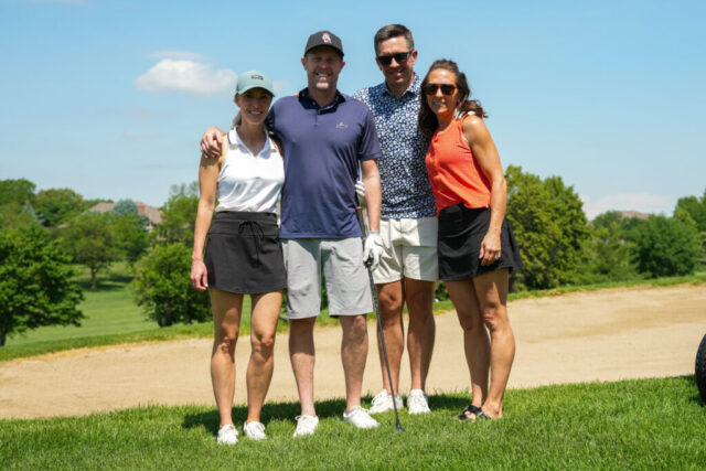 A group of two men and two ladies smiling on the green.