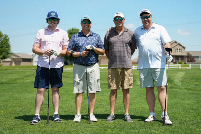 Four gentlemen are smiling on the green for a group photo.