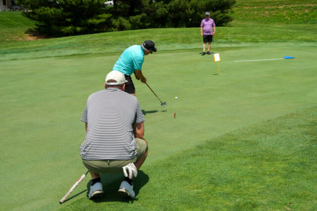 A man is swinging while two others watch.