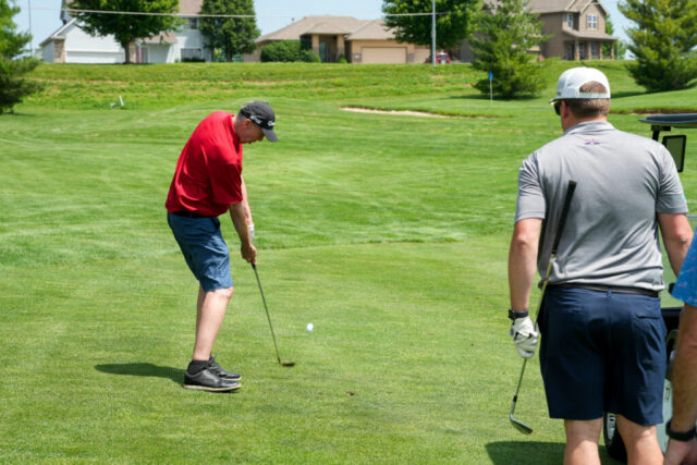 A man is swinging his club on the green.