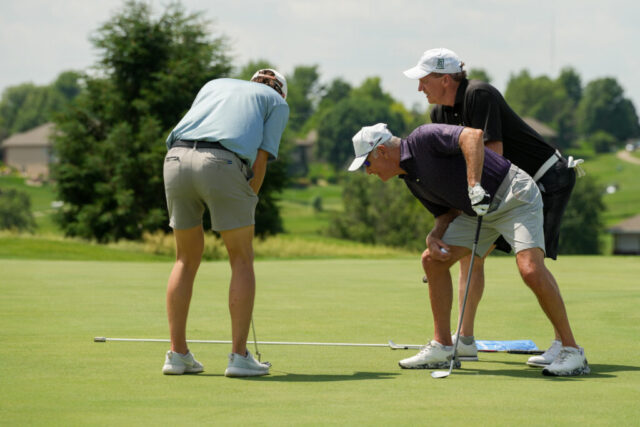Kevin and another man watching a man putt.