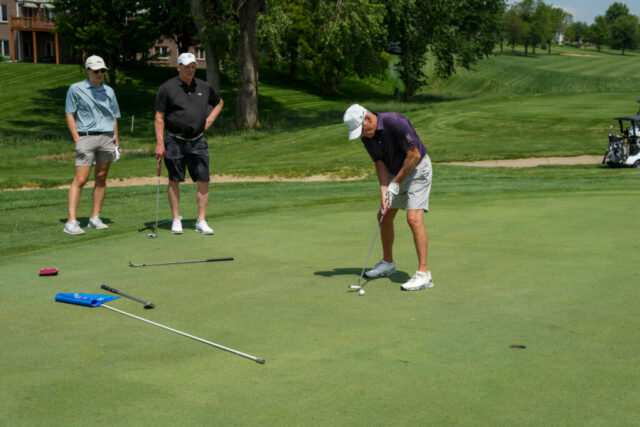 Kevin and another man watching a man putt.