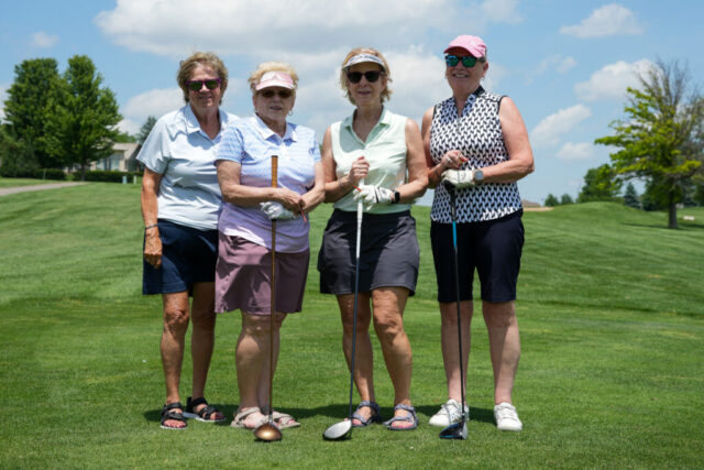 Four ladies are smiling on the green for a group photo.