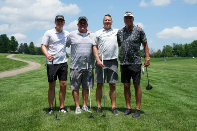 Four gentlemen are smiling on the green for a group photo.