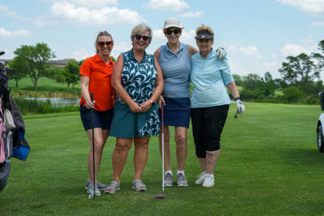 Four ladies are smiling on the green for a group photo.