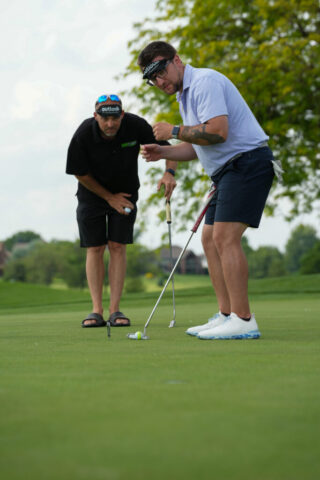 Nick is getting ready to putt while another watches behind him.