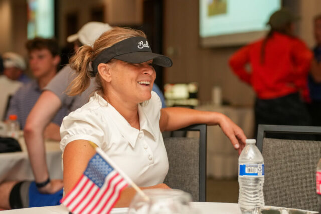 Megan Mackie is sitting at a dinner table smiling.