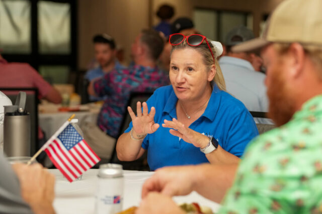 A lady is at a dinner table and talking with her hands.