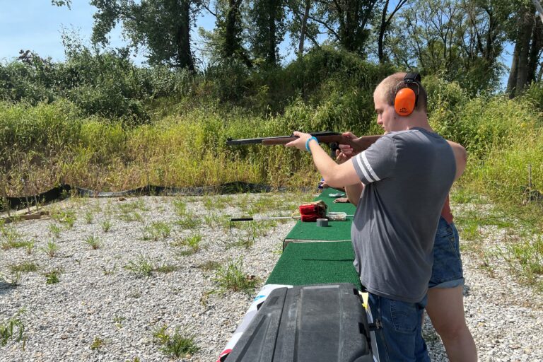 Jayden aiming a firearm at an indoor shooting range wearing ear protection