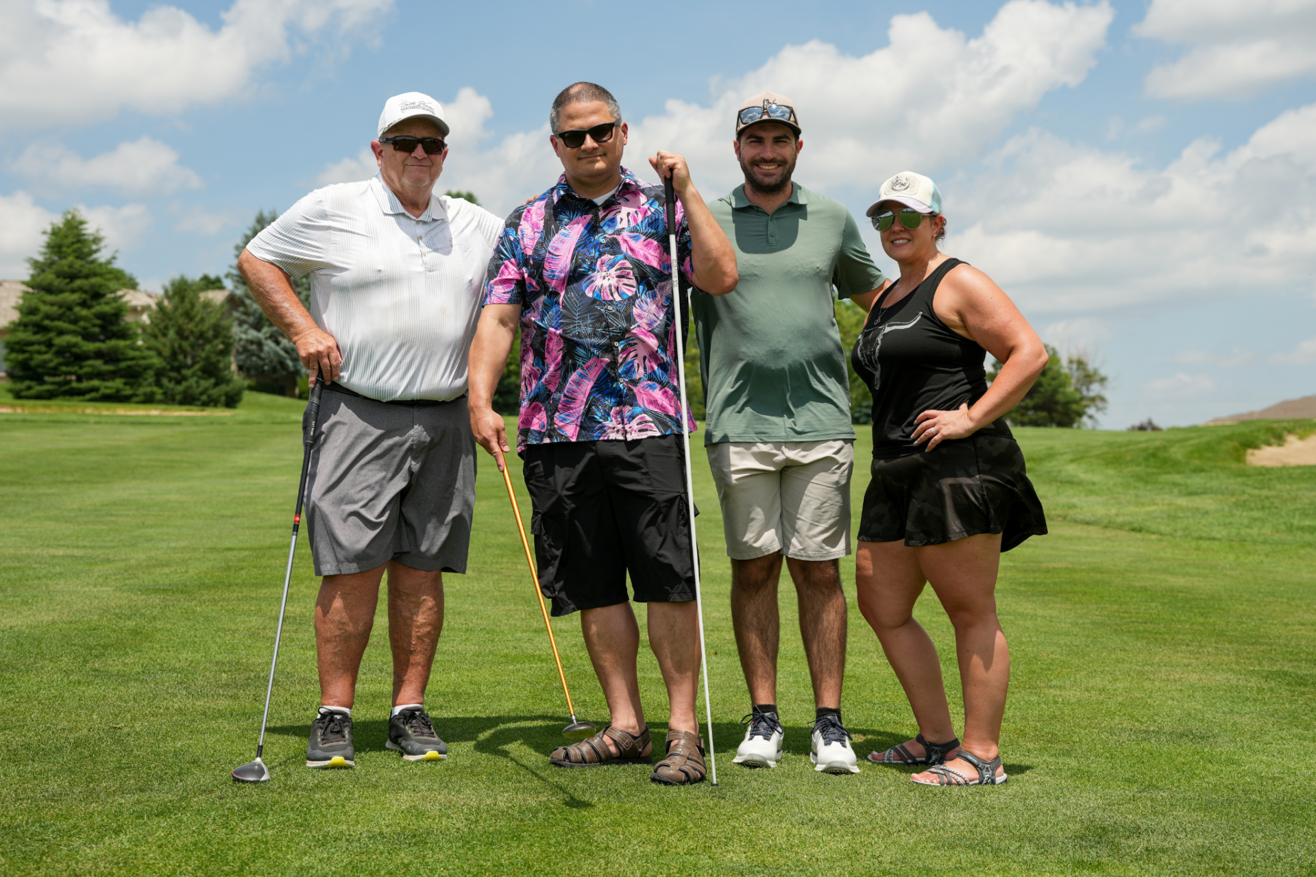 Two blind golfers, Ross and Marisa, with their two male guides on the course, smiling for a photo.