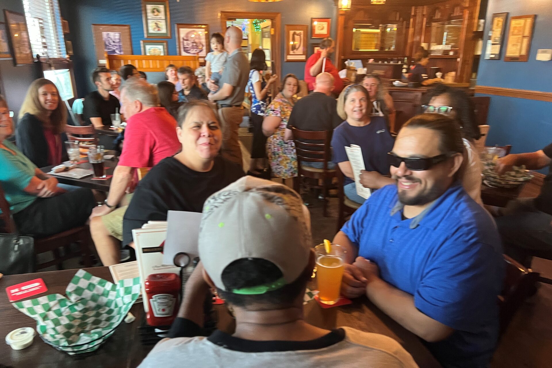 A large group of at least 40 people sitting at tables in a restaurant celebrating white cane day in 2025