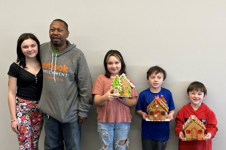 Alex lined up with 4 of his grandkids showing off the gingerbread houses they just put together with icing and candy.