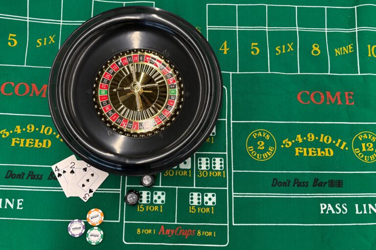 A table with a green felt betting table. On top of it there is a roulette wheele, braille dice, special Outlook chips, large print braille playing cards